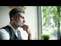 serious mature man sitting at the table in a cafe working slow